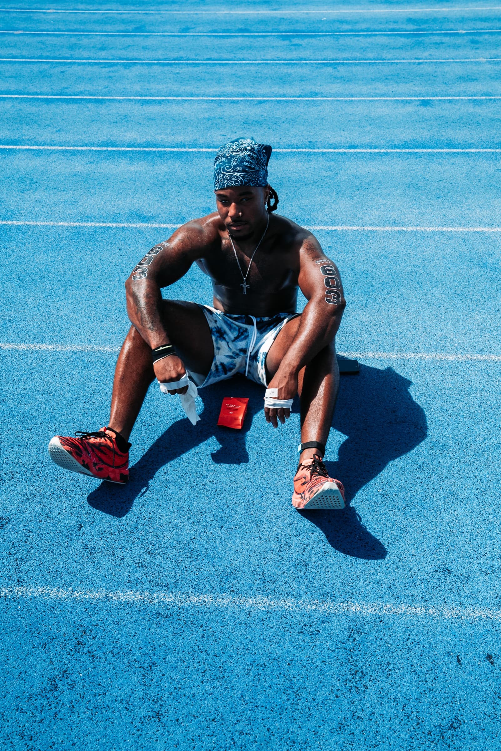 Athlete seated on a blue running track, seen from above